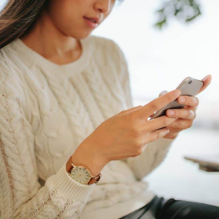 Young woman reading text message on her smartphone